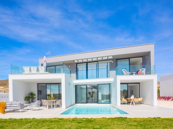 Front view of a two-storey white villa with pool, terrace seating and glass balustrade