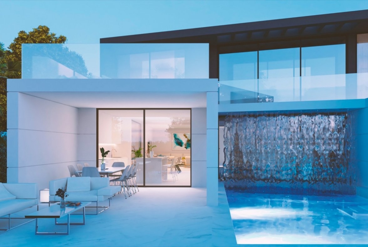 Covered patio seating area beside illuminated pool with cascading water feature