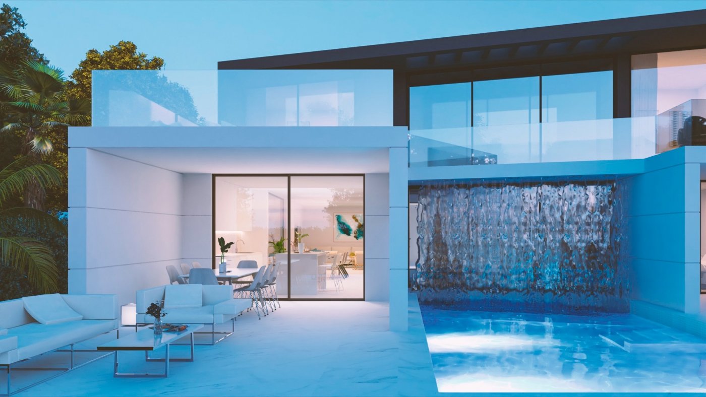 Covered patio seating area beside illuminated pool with cascading water feature