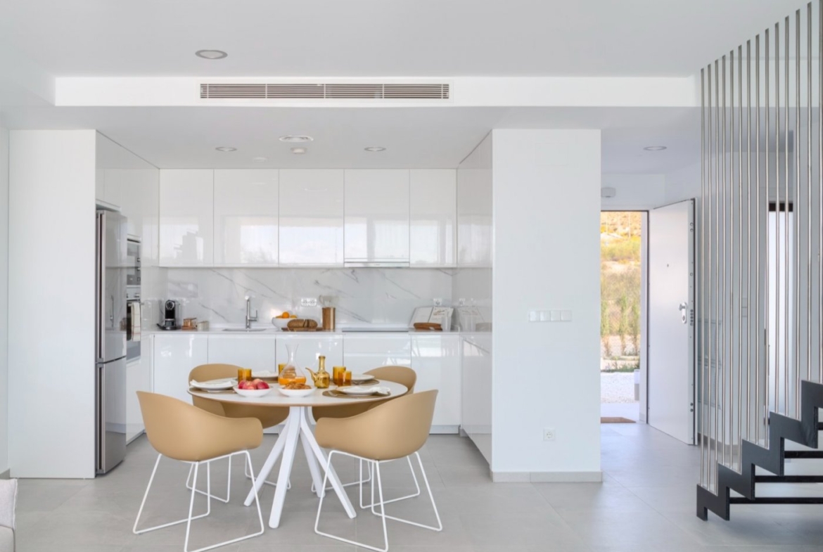 Compact white kitchen with round dining table and view toward entrance