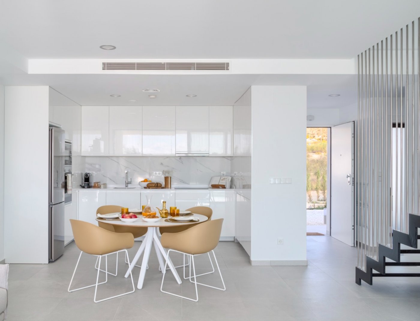 Compact white kitchen with round dining table and view toward entrance