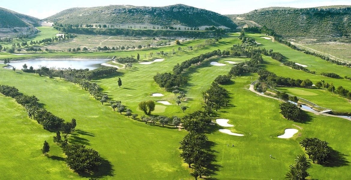 Aerial view of manicured golf course showing fairways, bunkers and water hazard