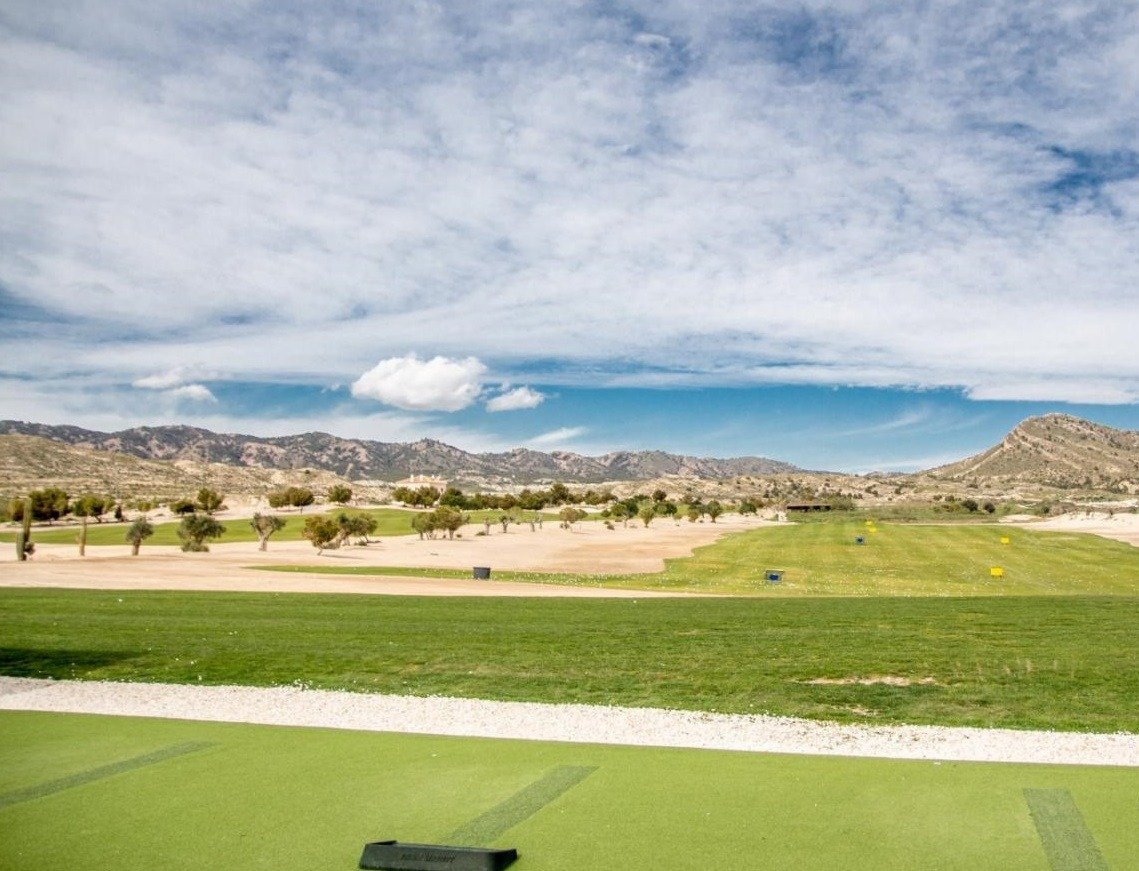 Golf driving range foreground with dry landscape and low mountains on the horizon