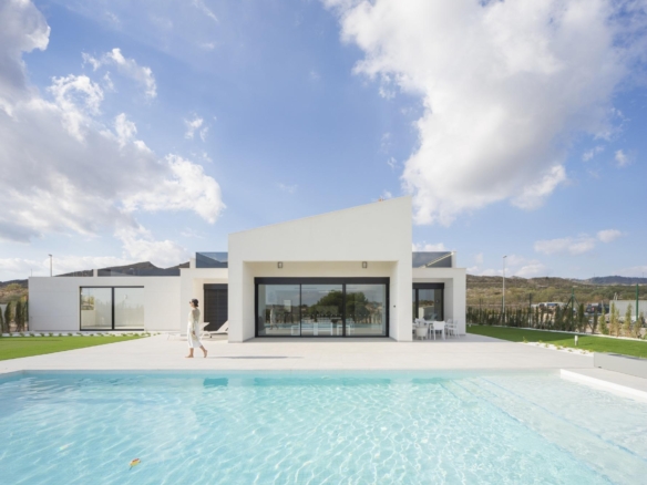 Single-storey white villa rear facade with pool, terrace and a person walking nearby