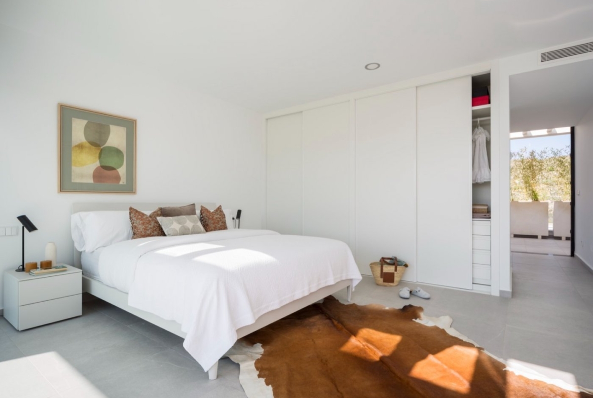 Bright bedroom with double bed, built-in sliding wardrobes and sunlight on floor