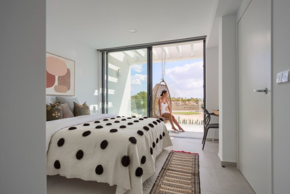 Bedroom interior with sliding doors to balcony and hanging egg chair outside