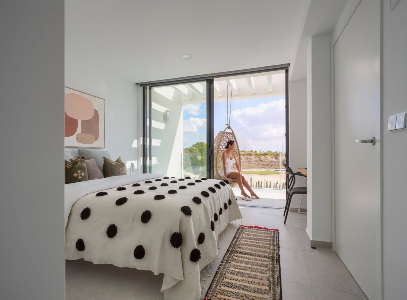 Bedroom interior with sliding doors to balcony and hanging egg chair outside