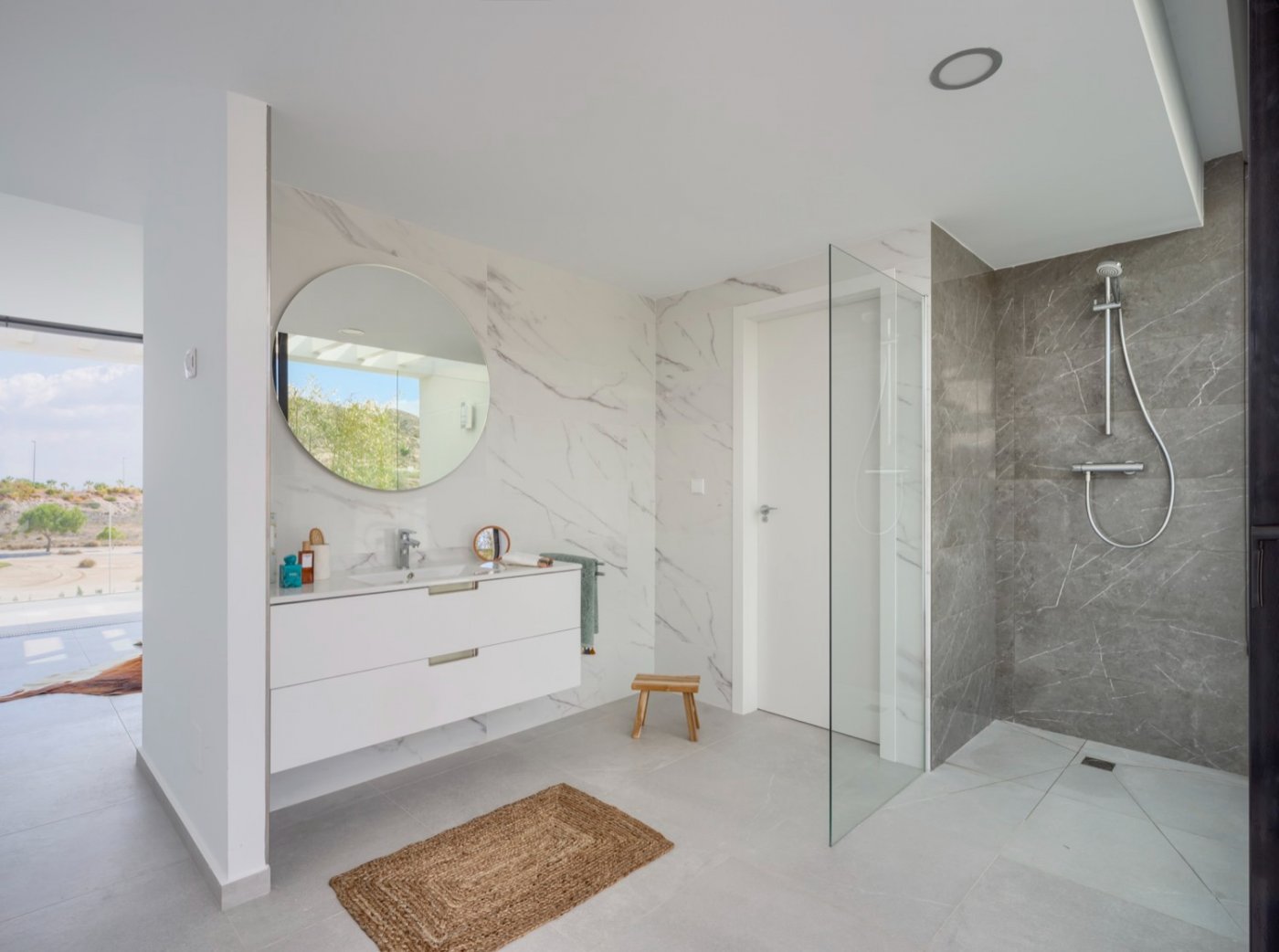 Bathroom with circular mirror, white vanity unit and walk-in shower area