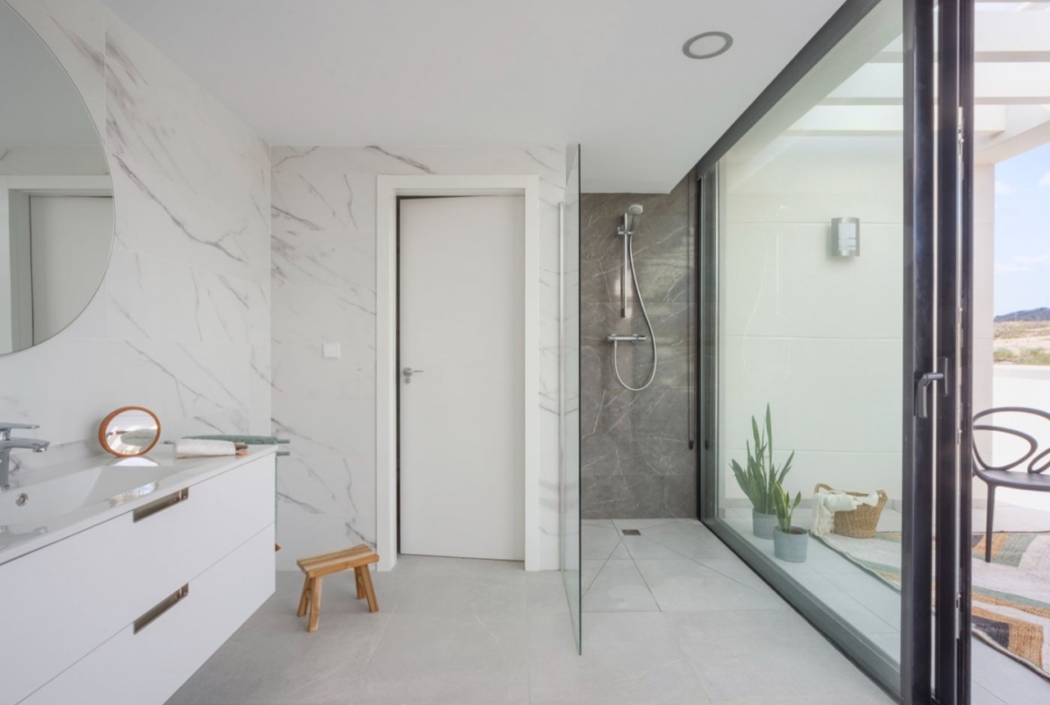 Shower area with glass partition and sliding doors opening onto a tiled terrace