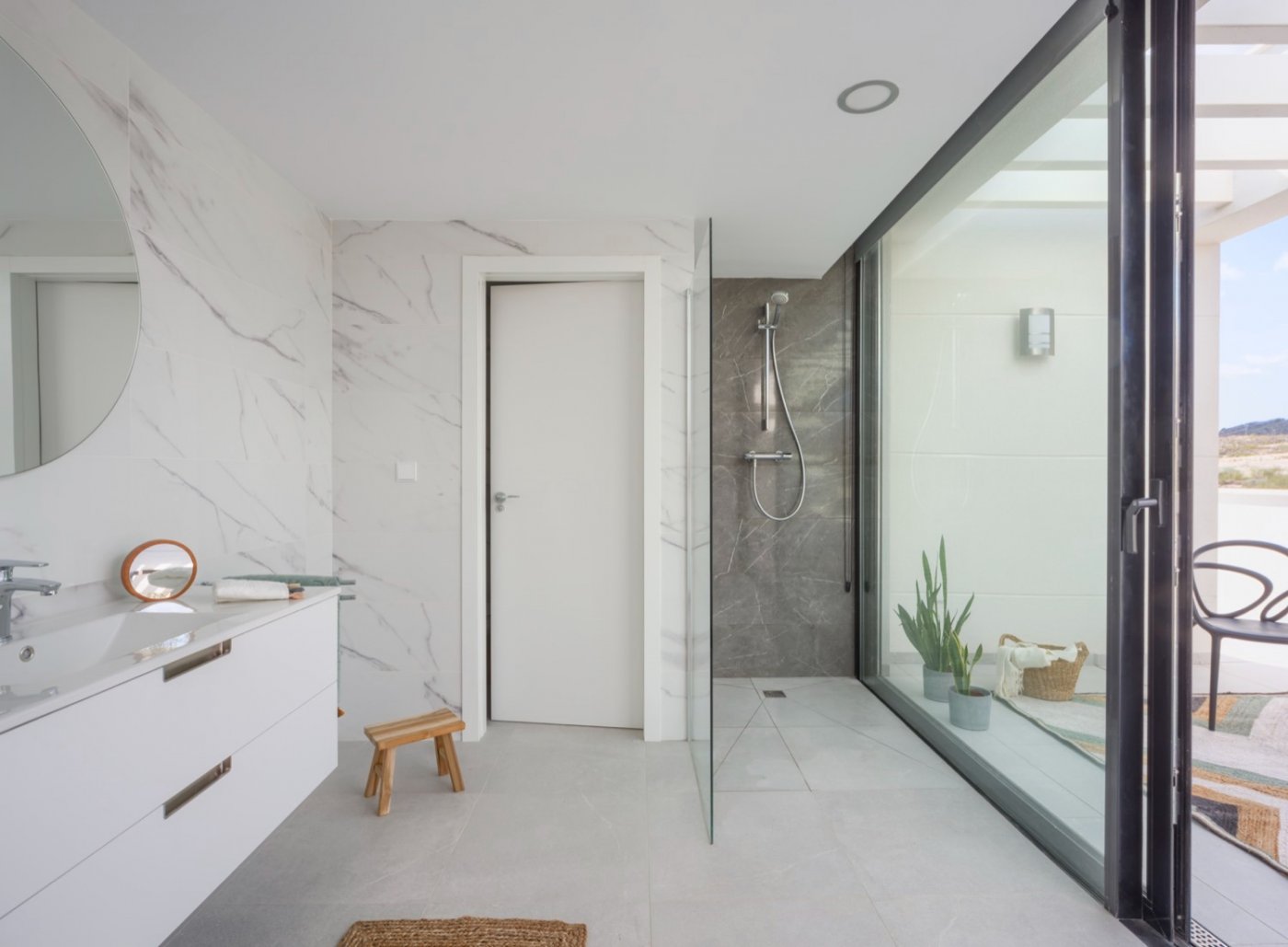 Shower area with glass partition and sliding doors opening onto a tiled terrace