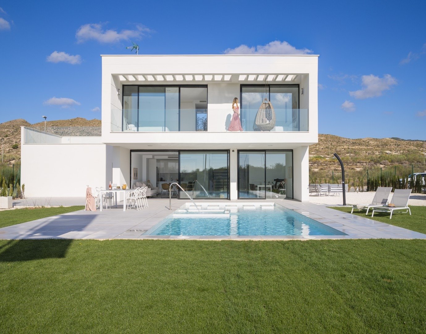 Two-storey white villa facade with ground-floor pool, terrace and upper balcony