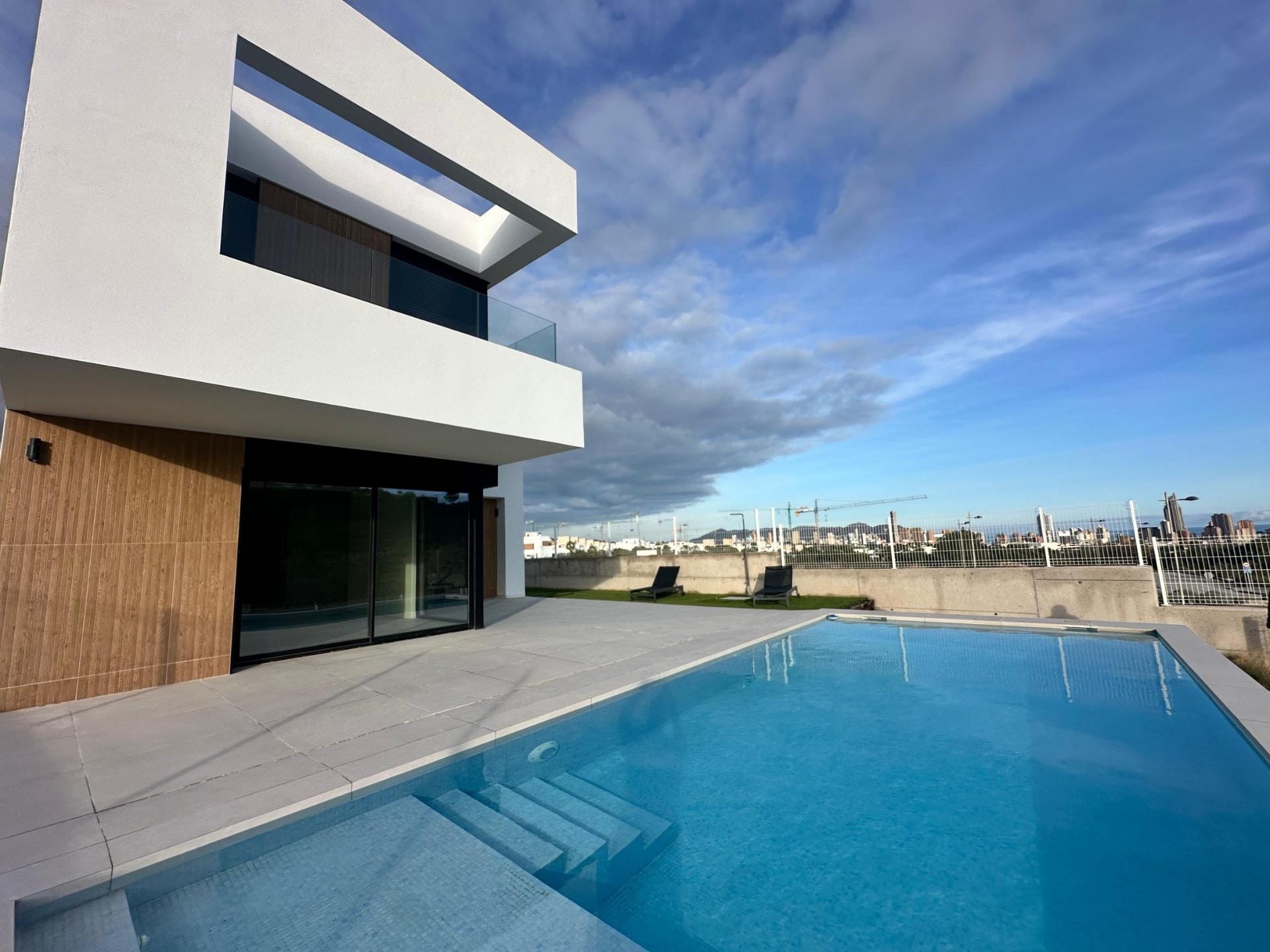 NEW-BUILD-VILLAS-IN-BALCON-DE-FINESTRAT-2 Swimming pool beside a white villa with timber-effect exterior accents in Finestrat, Alicante