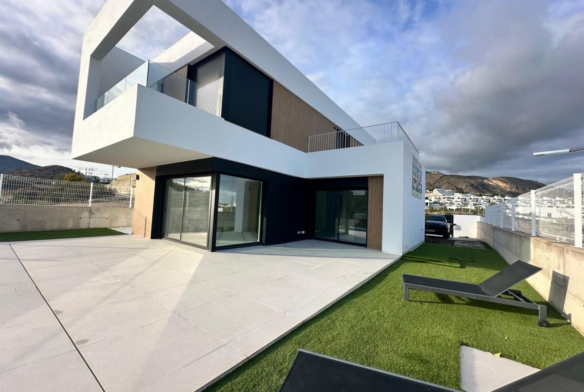 Garden seating area and covered terrace beside a two-storey villa in Finestrat, Alicante