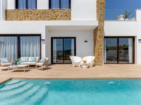 Private swimming pool beside the stone-detailed villa façade in Balcón de Finestrat, Alicante