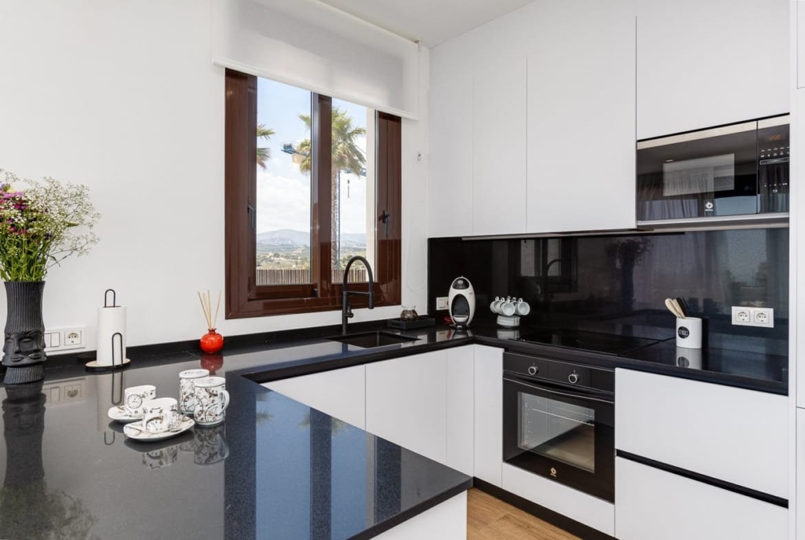 Fitted kitchen with black worktop and window in Balcón de Finestrat, Alicante