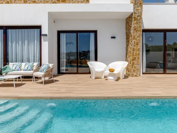 Private swimming pool beside the stone-detailed villa façade in Balcón de Finestrat, Alicante