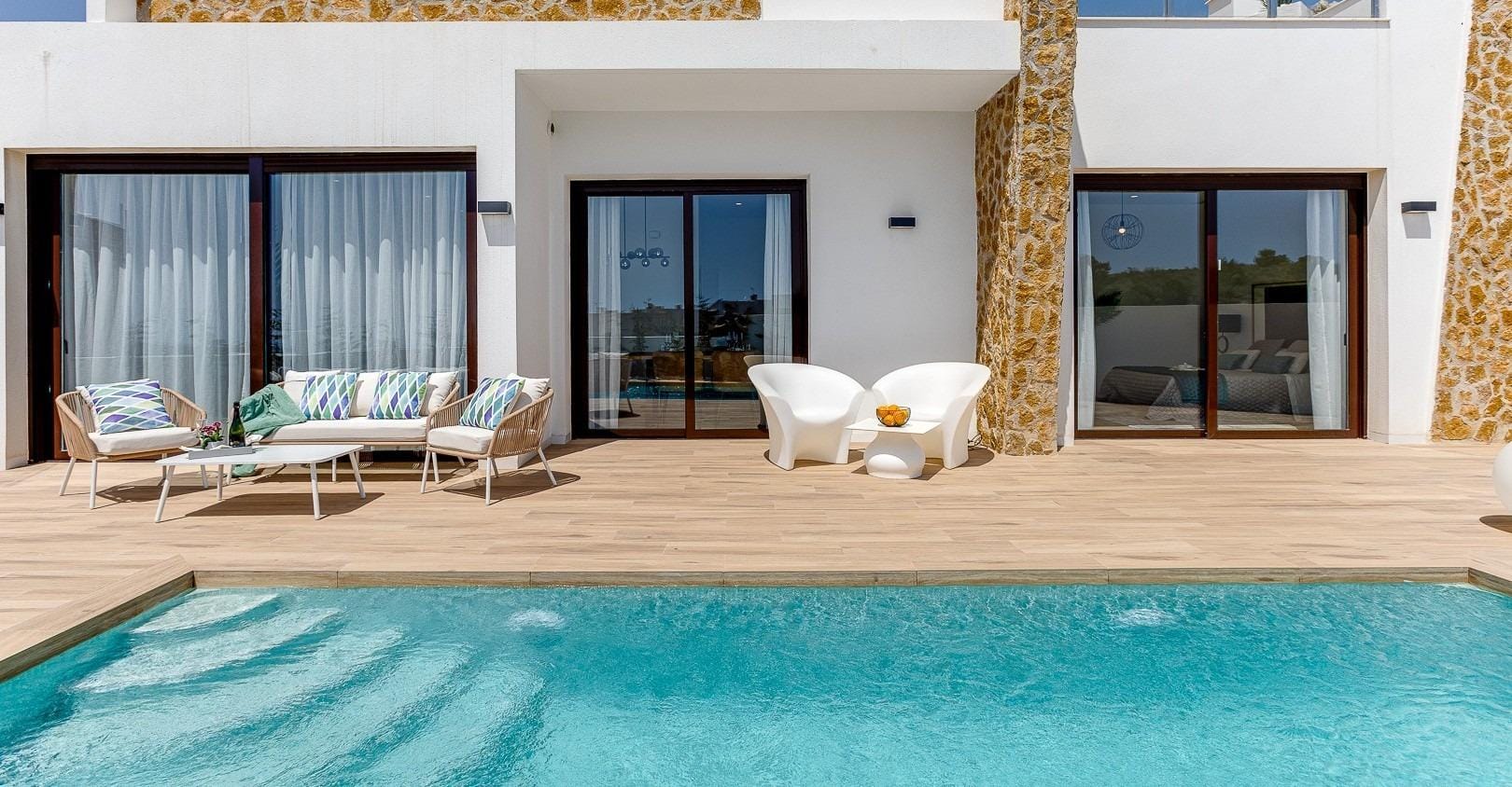 NEW BUILD VILLAS IN BALCON DE FINESTRAT Private swimming pool beside the stone-detailed villa façade in Balcón de Finestrat, Alicante