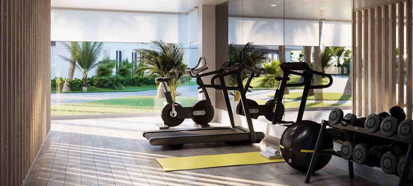 Rendering of the communal gym with exercise bikes, weights and garden-facing glazing in Jávea, Alicante