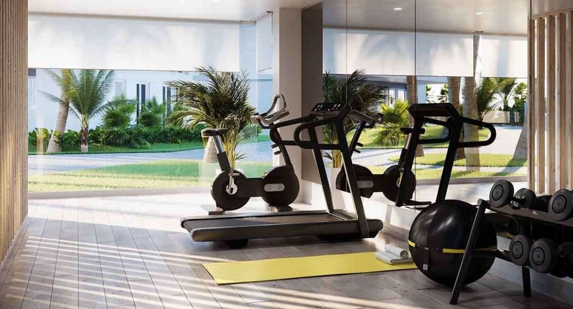 Rendering of the communal gym with exercise bikes, weights and garden-facing glazing in Jávea, Alicante