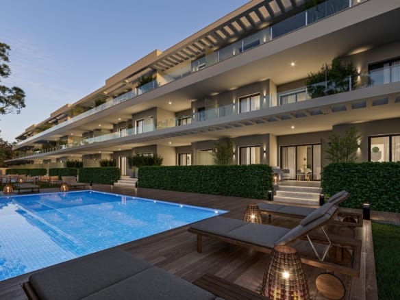 Apartment balconies beside a lit communal swimming pool and sun loungers at dusk in Los Narejos, Murcia