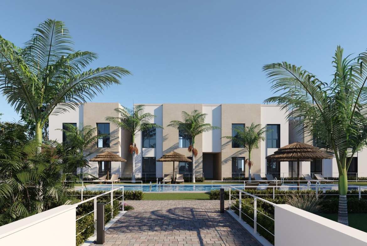 Resort-style pool view with palm trees and two-storey apartment facades beyond