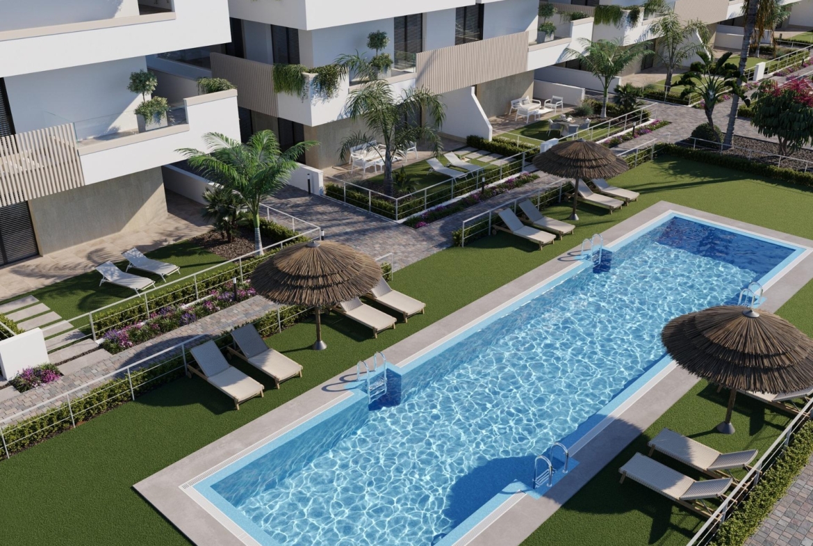 Communal rectangular swimming pool with sunloungers, parasols and paved poolside lawn area