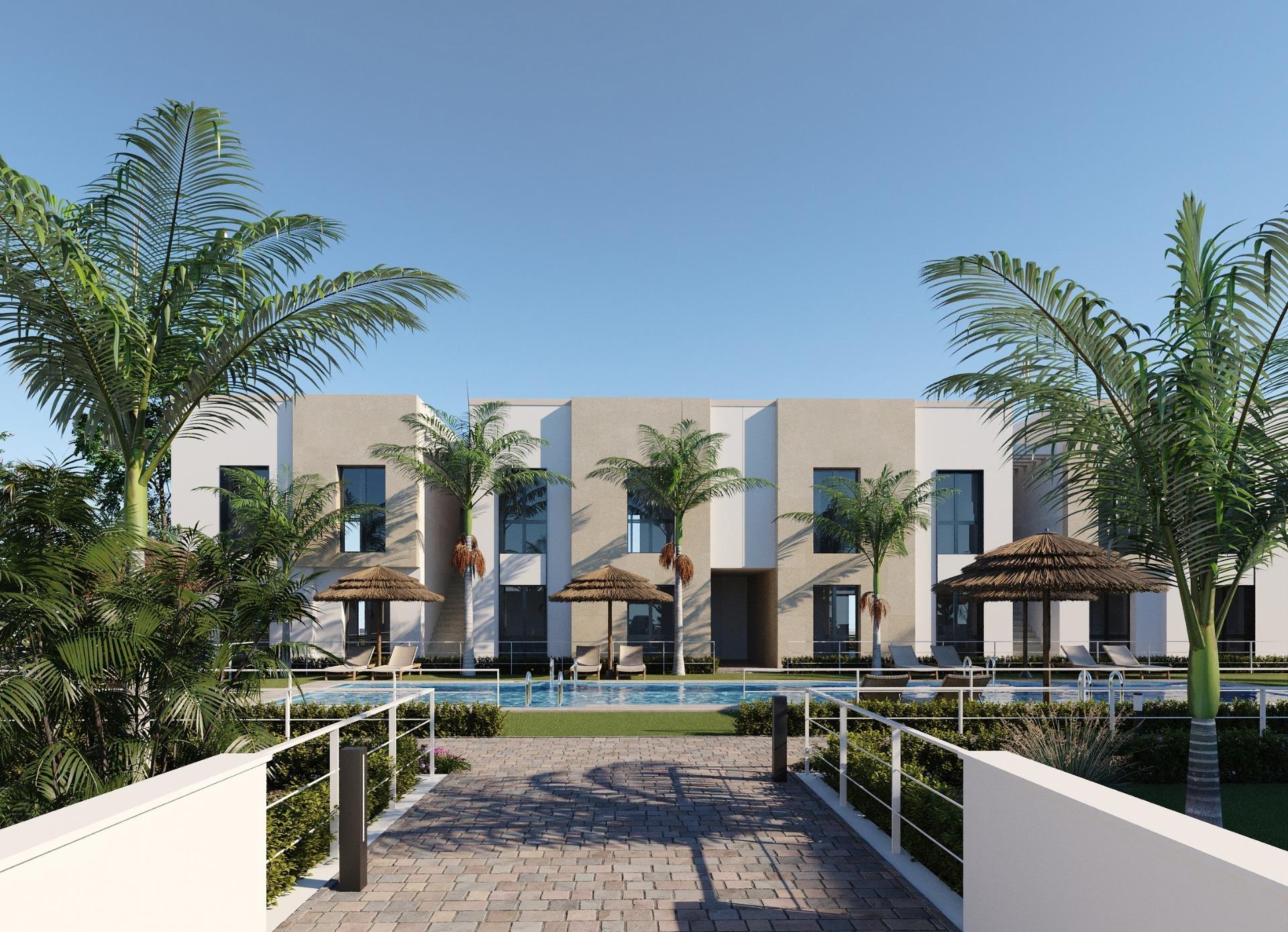 Modern low-rise apartments with central swimming pool, sunbeds and palm trees in foreground