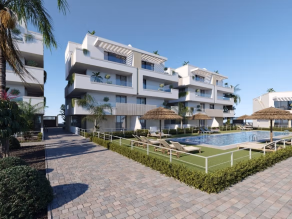 Modern white apartment block beside communal pool with straw parasols and sun loungers