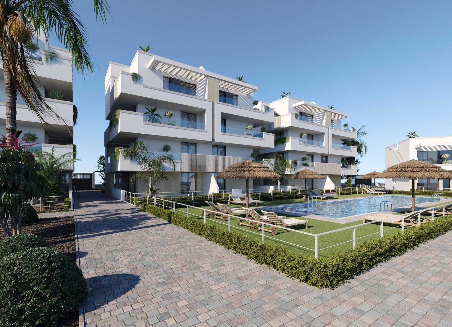 New Build Apartments and Bungalows in Santa Rosalia Lake and Life Resort Modern white apartment block beside communal pool with straw parasols and sun loungers