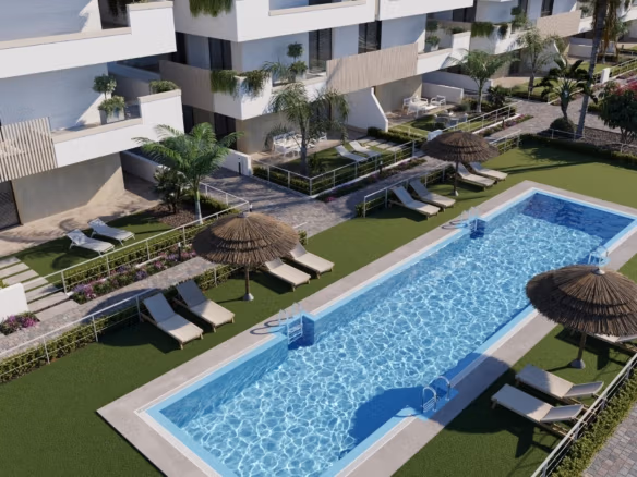 Communal swimming pool with sunloungers and thatched parasols beside ground-floor terraces