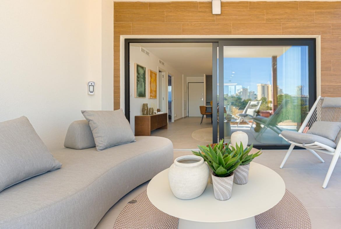 Covered terrace with lounge seating opening into a bright modern apartment