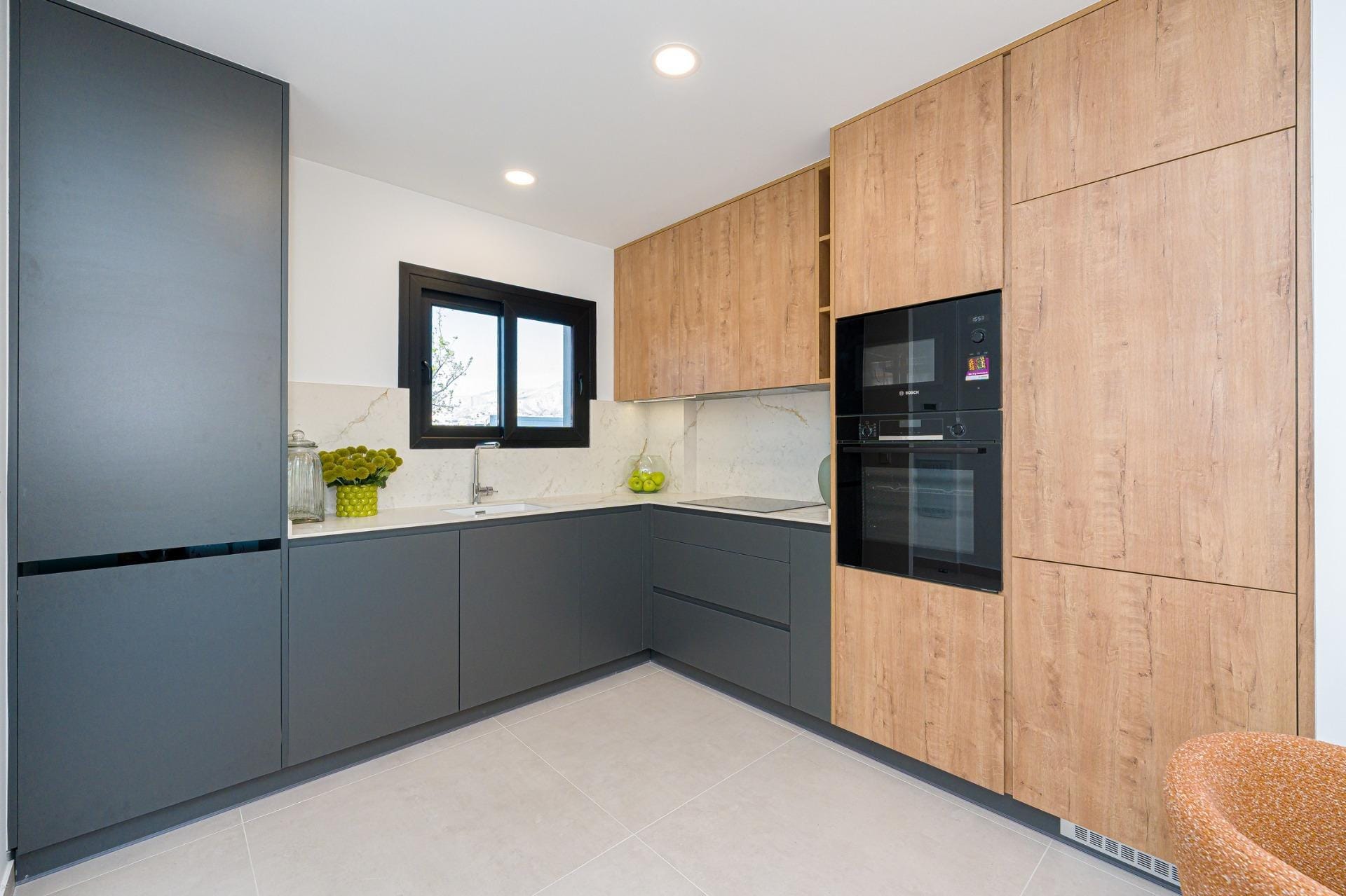 Modern L-shaped kitchen with integrated appliances and stone-look splashback