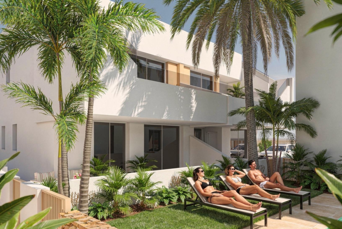 Sunbathers on loungers beside planted terraces in front of a white, modern apartment façade