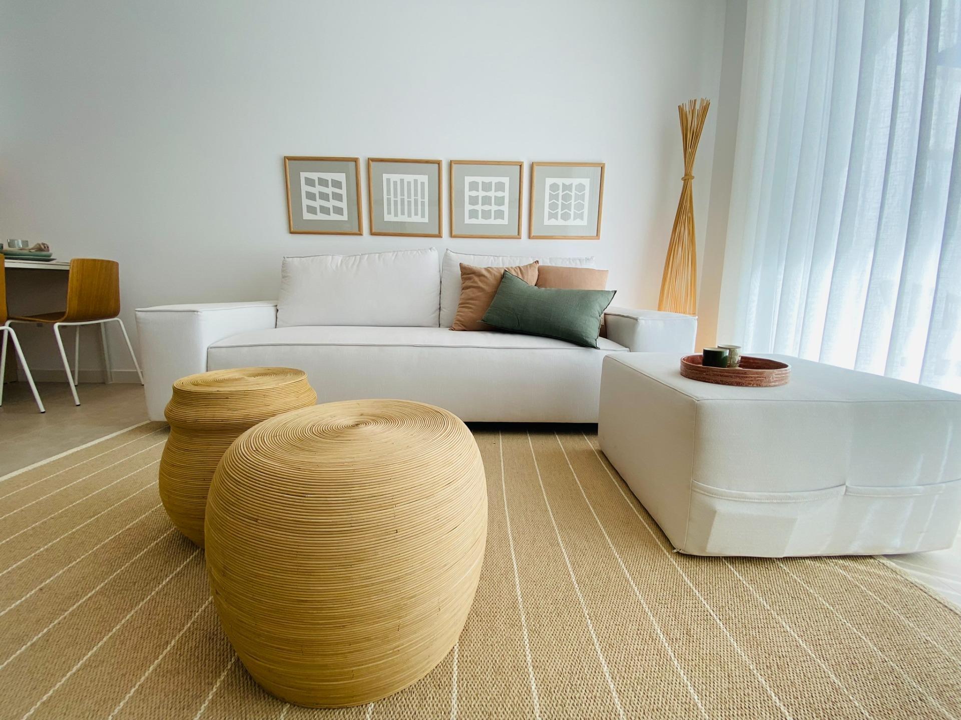 Cream sofa against white wall with two round woven coffee tables on a rug