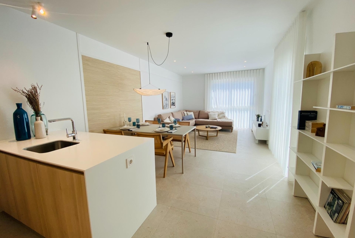 Open-plan kitchen and dining area flowing into a bright living space with large window