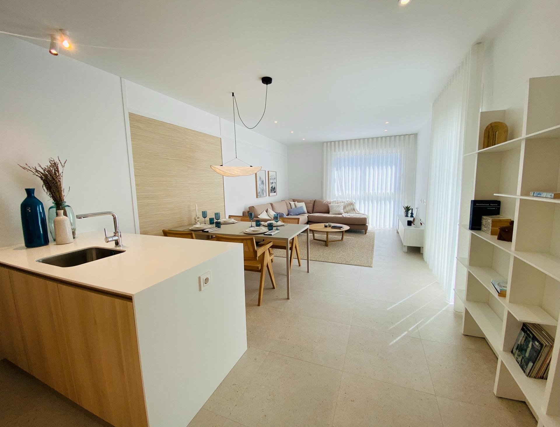 Open-plan kitchen and dining area flowing into a bright living space with large window