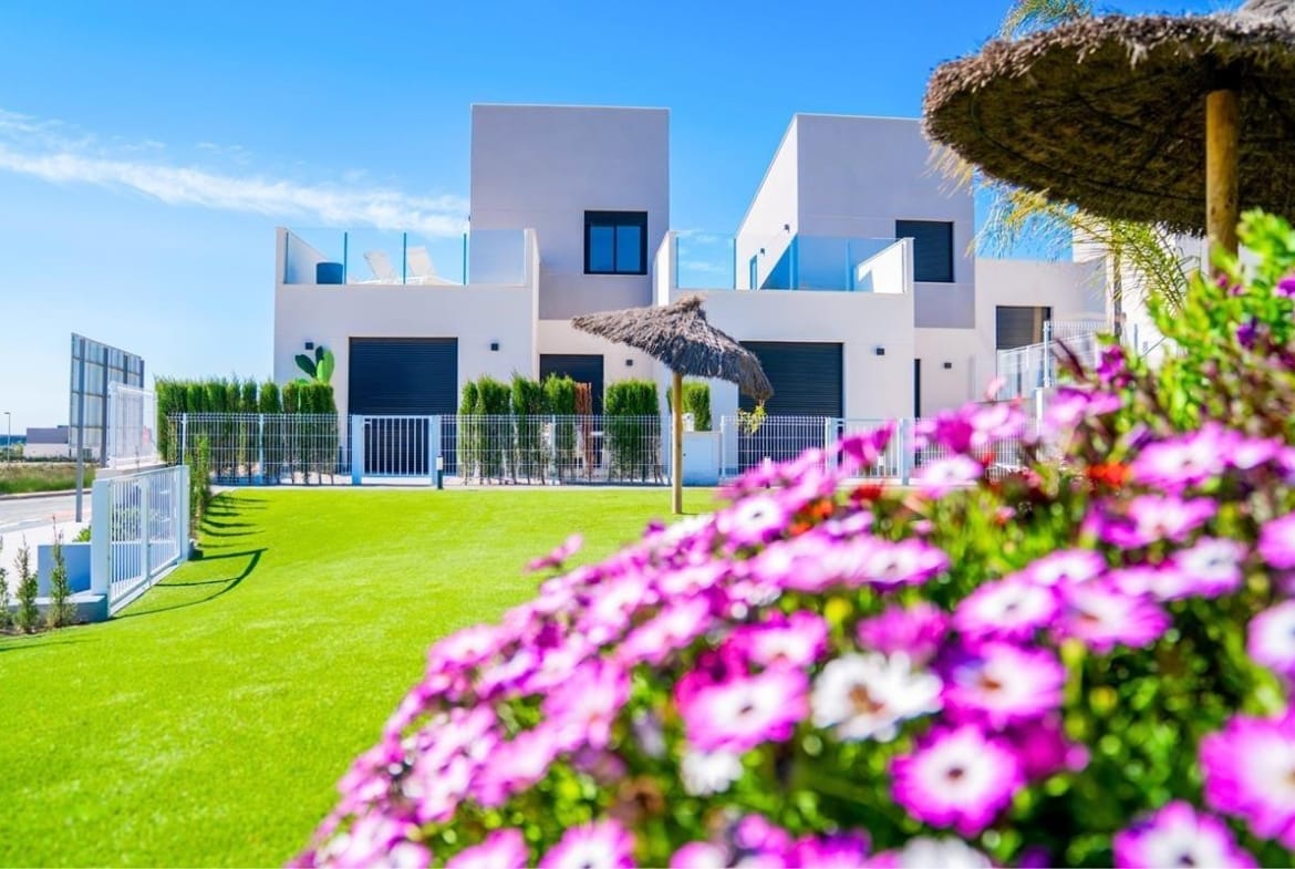 Landscaped communal garden with flowering plants beside white homes in Altaona Golf, Baños y Mendigo, Murcia
