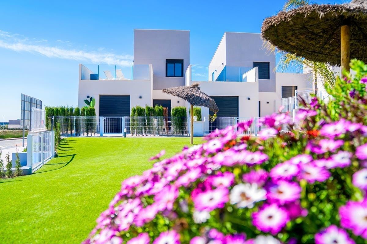 Landscaped communal garden with flowering plants beside white homes in Altaona Golf, Baños y Mendigo, Murcia