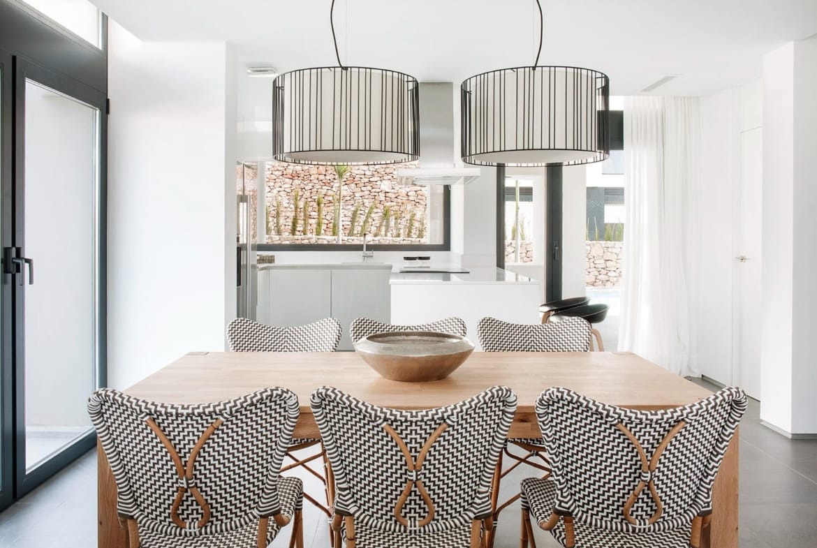 Dining table facing a bright white kitchen with broad windows in La Manga Club, Murcia