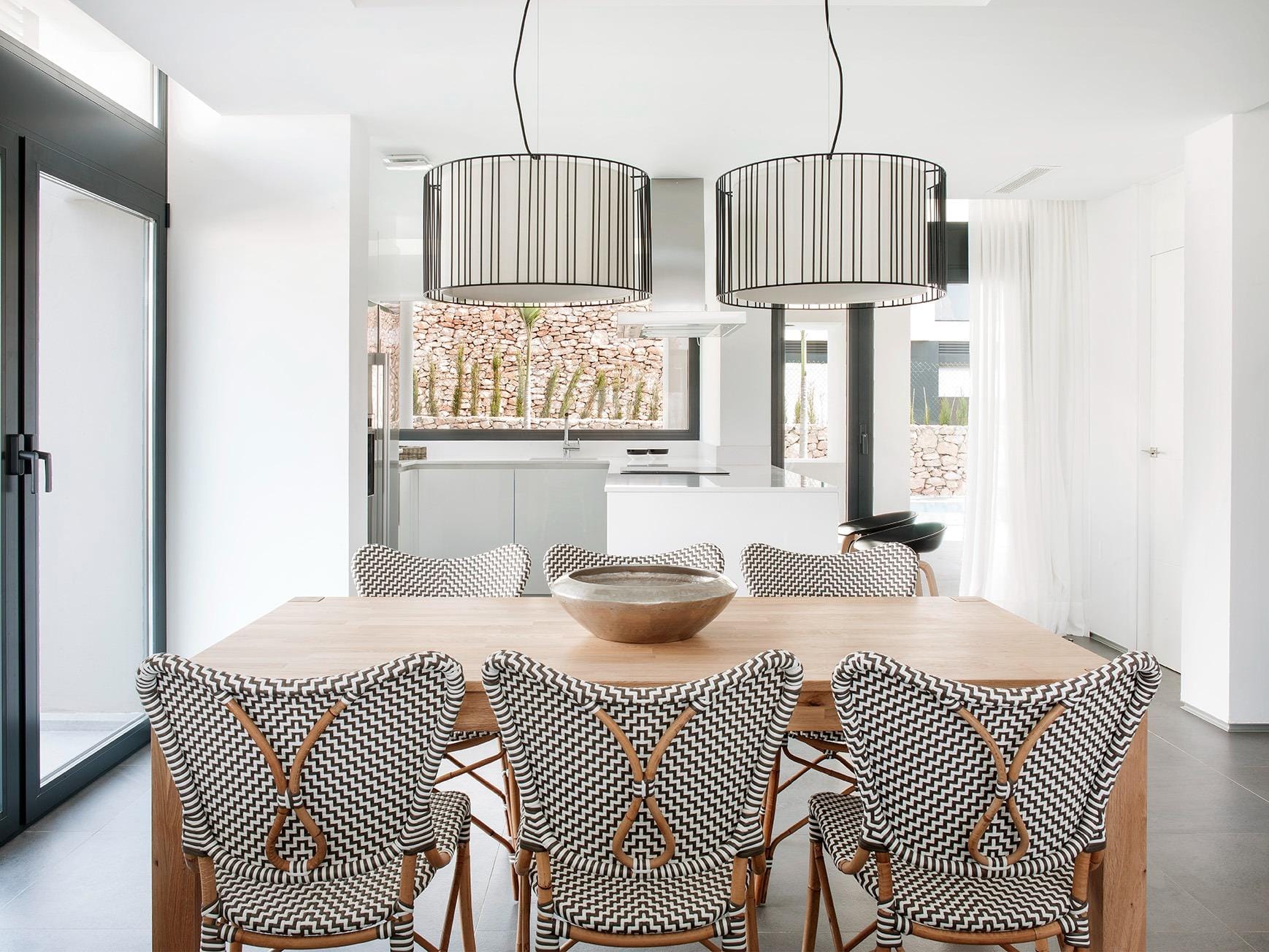 New-Build-Villas-for-Sale-at-La-Manga-Club-–-Luxury-Living-in-a-Prestigious-Resort-11 Dining table facing a bright white kitchen with broad windows in La Manga Club, Murcia