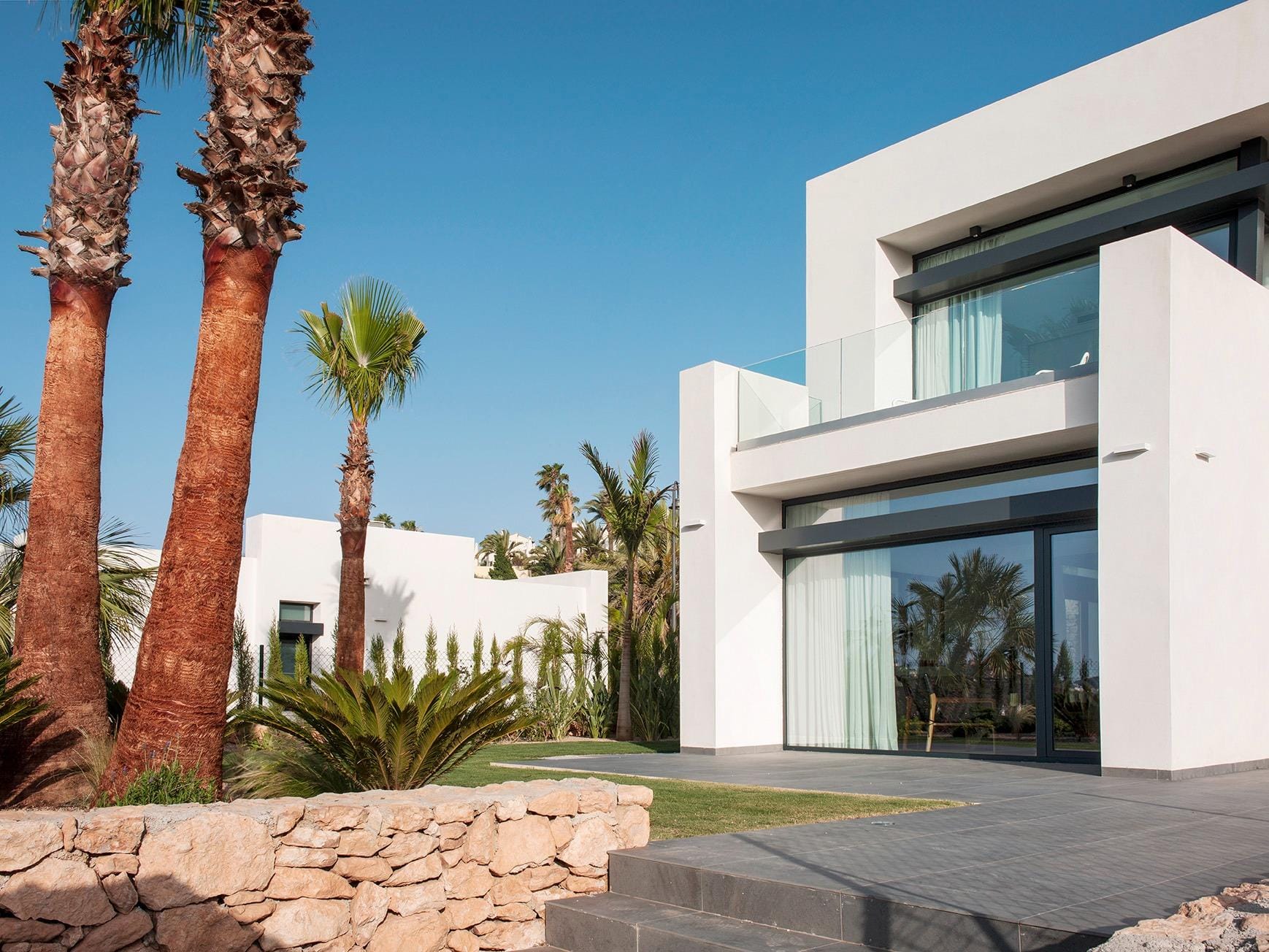 New Build Villas for Sale at La Manga Club – Luxury Living in a Prestigious Resort Modern white villa exterior with large glass doors, upper terrace and landscaped garden in La Manga Club, Murcia