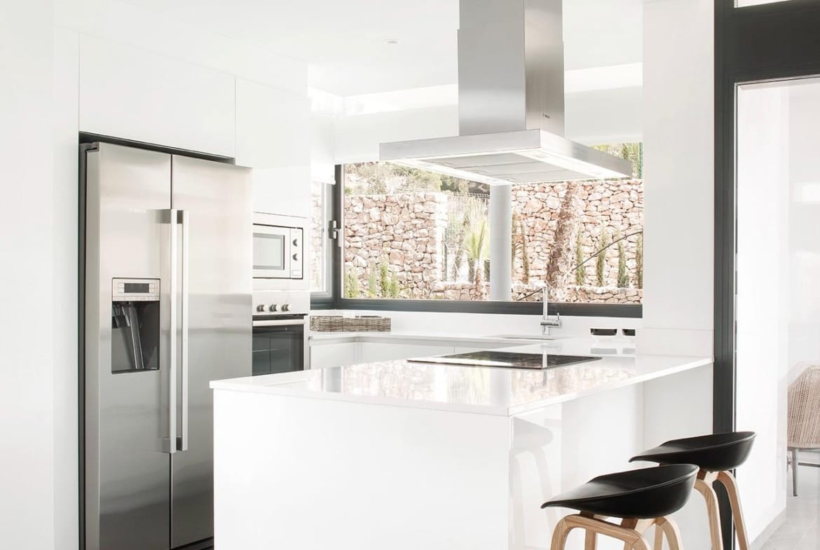Minimalist white kitchen with island, breakfast seating and fitted appliances in La Manga Club, Murcia