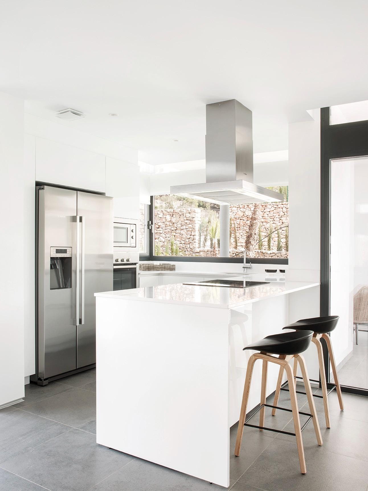 New-Build-Villas-for-Sale-at-La-Manga-Club-–-Luxury-Living-in-a-Prestigious-Resort-12 Minimalist white kitchen with island, breakfast seating and fitted appliances in La Manga Club, Murcia