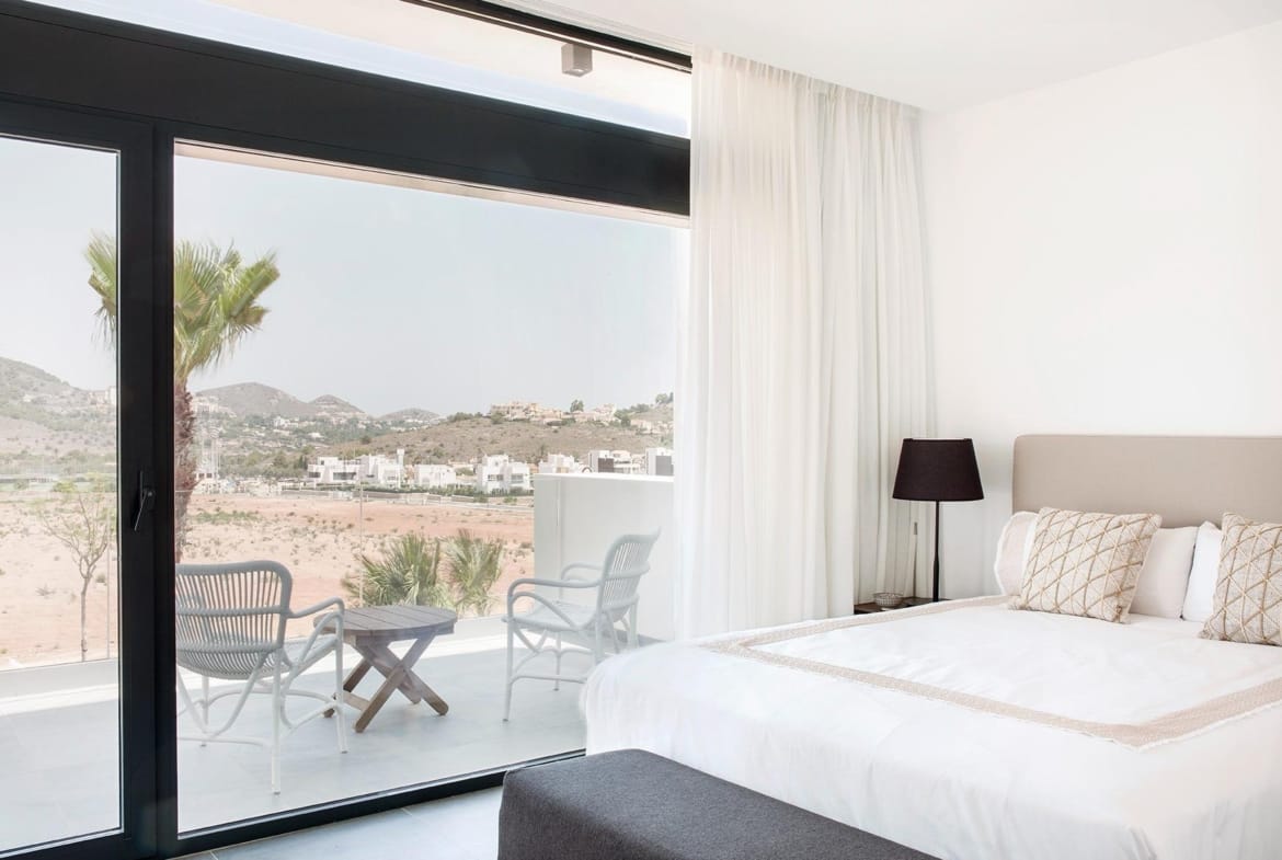 Bedroom with floor-to-ceiling glass and a private terrace seating area in La Manga Club, Murcia