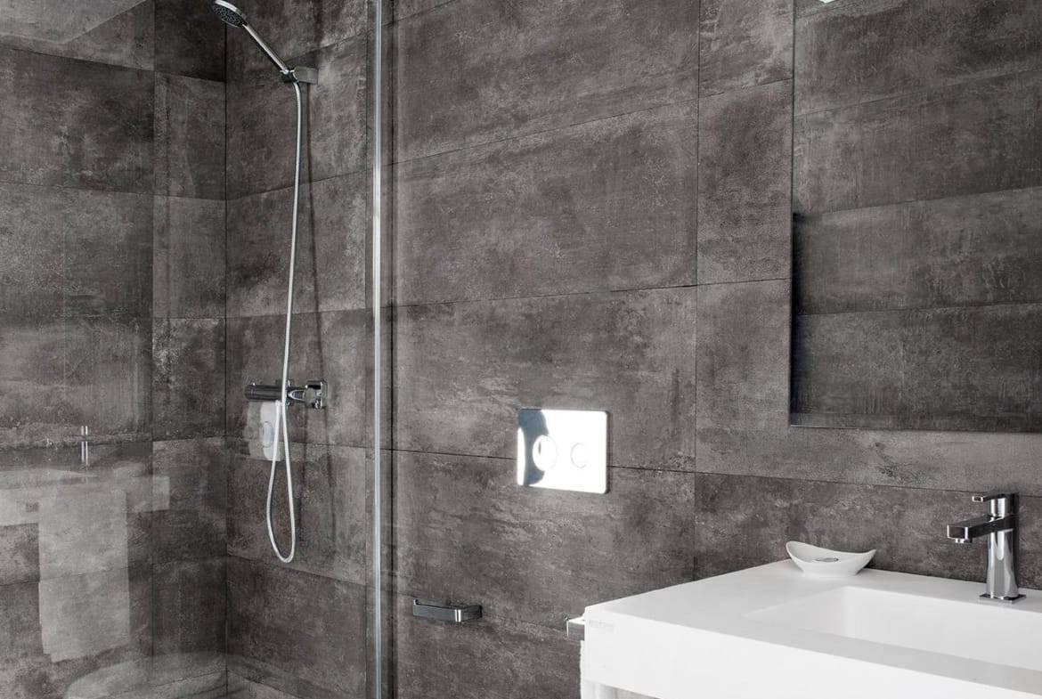 Modern bathroom with dark stone-look tiles and walk-in shower in La Manga Club, Murcia