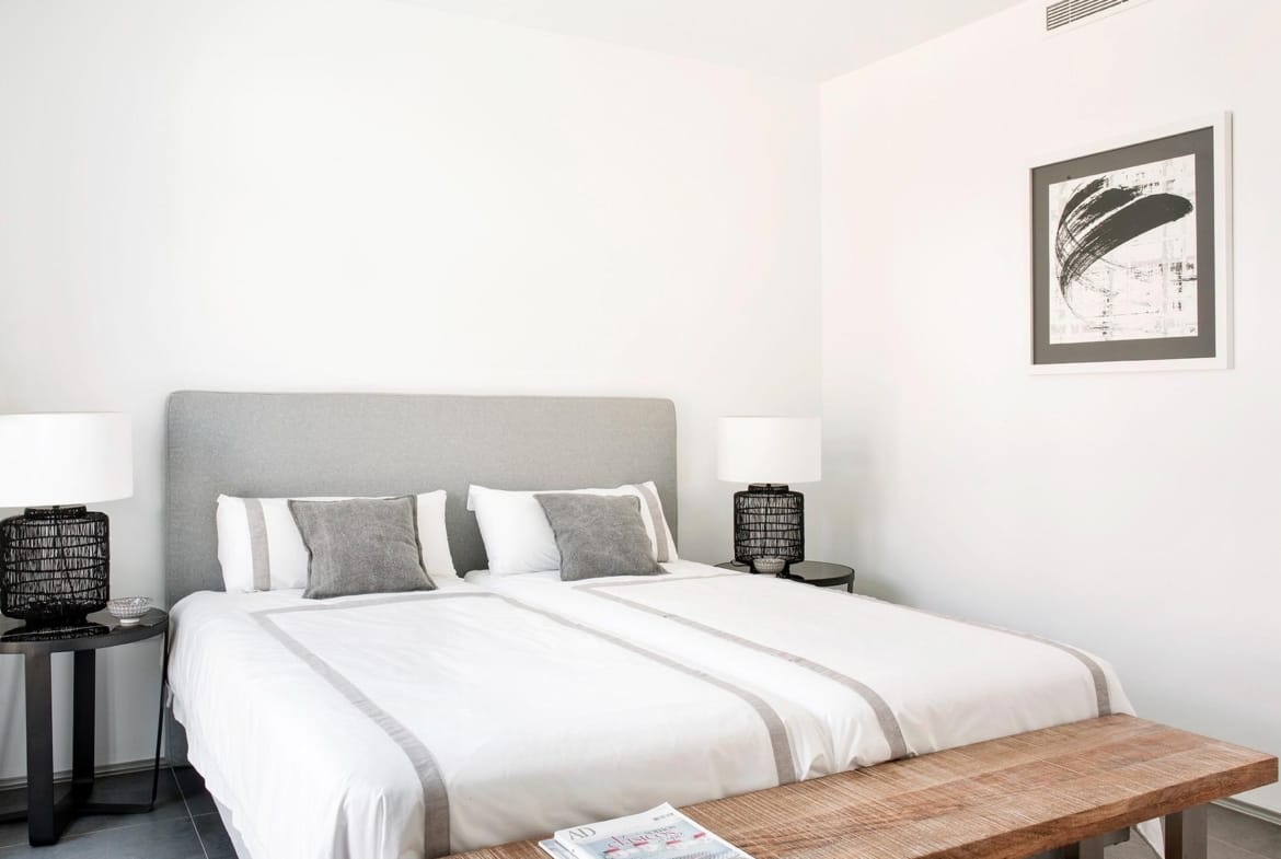 Twin bedroom with bedside lamps and a woven bench in La Manga Club, Murcia