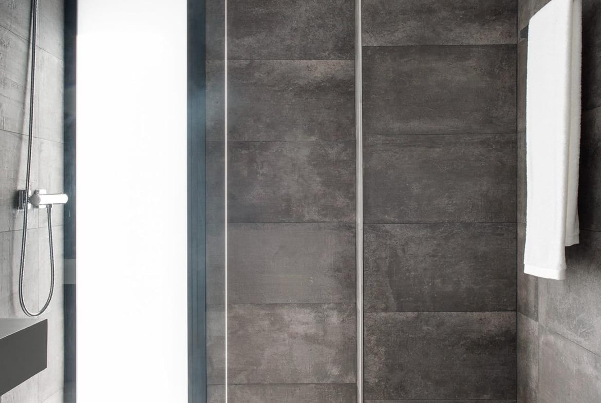 Walk-in shower with dark tiles and tall frosted window in La Manga Club, Murcia
