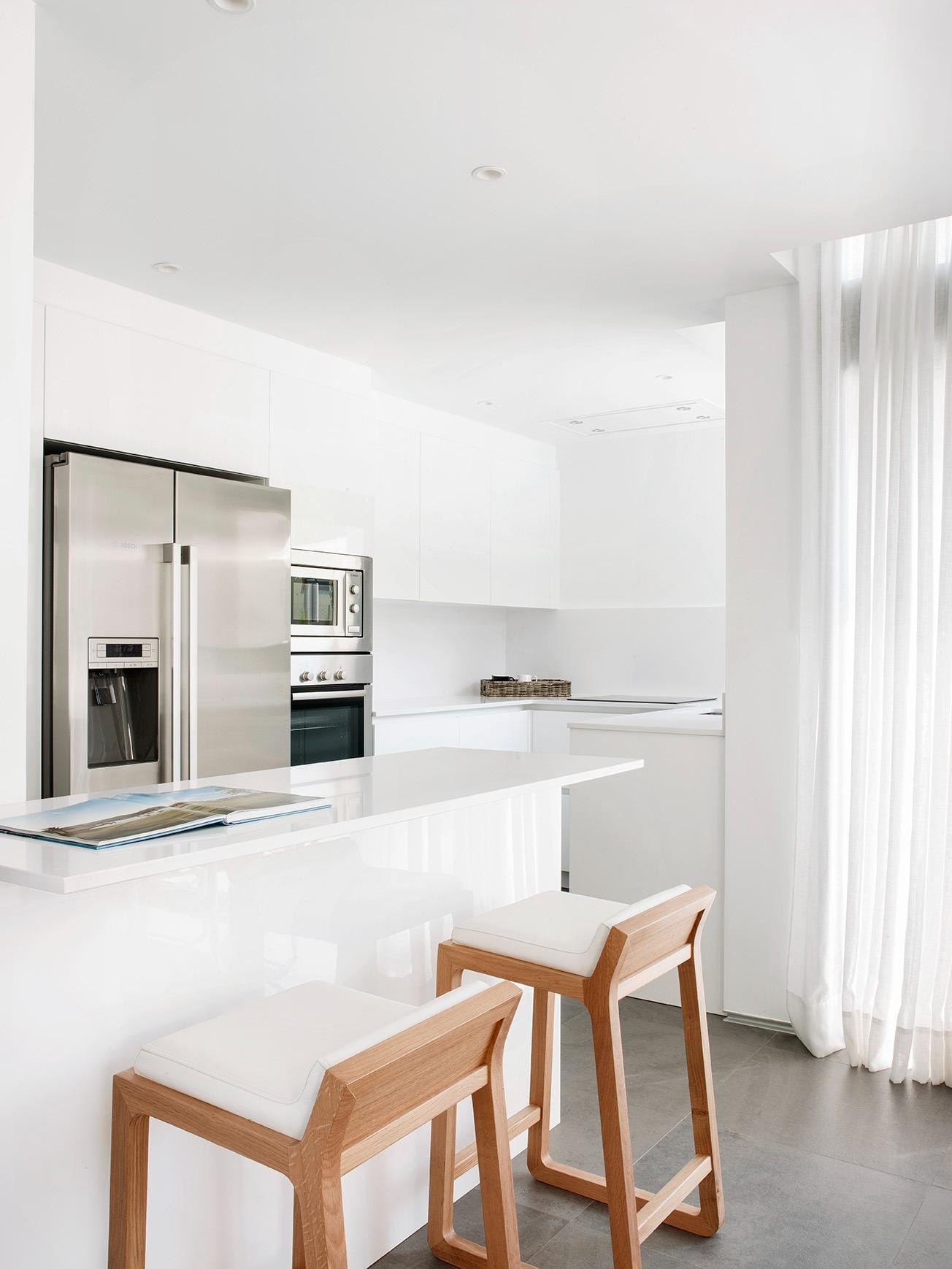 Minimalist white kitchen with breakfast bar and integrated appliances in La Manga Club, Murcia