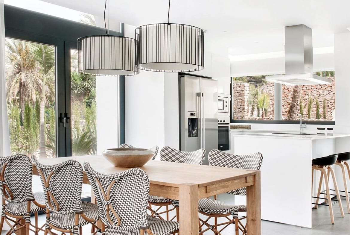 Dining area beside a minimalist white kitchen with island in La Manga Club, Murcia