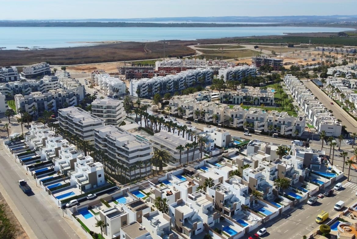 Rendering of a communal pool with sun loungers and curved apartment facades in El Raso, Guardamar del Segura, Alicante